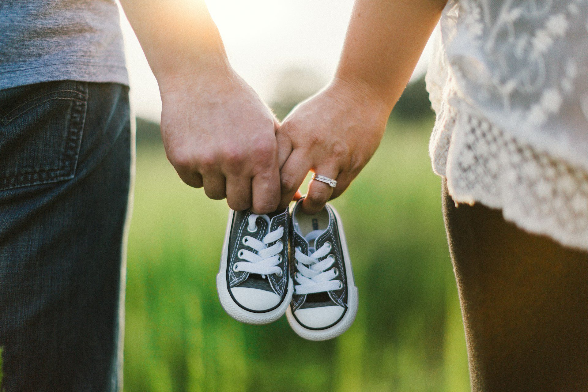 Baby shoes being held by dad on left and mom on right